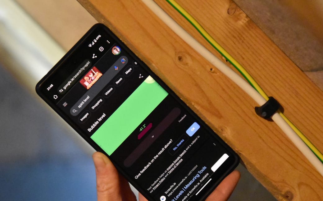 Google spirit level on a phone, held against a roof beam